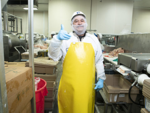 A meatpacking worker giving a thumbs up.