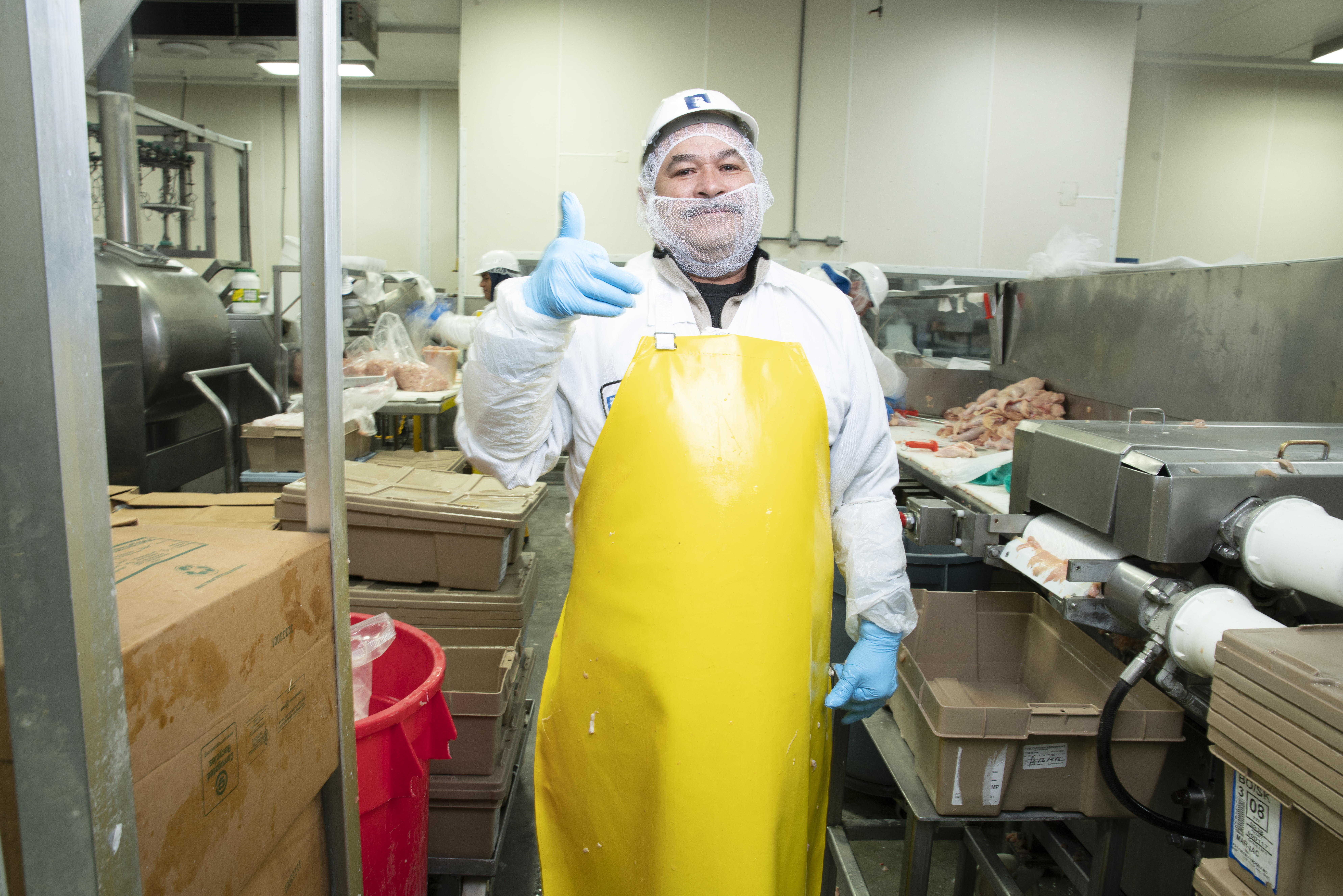 A meatpacking worker giving a thumbs up.