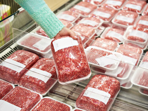 A woman picking up a ground beef package