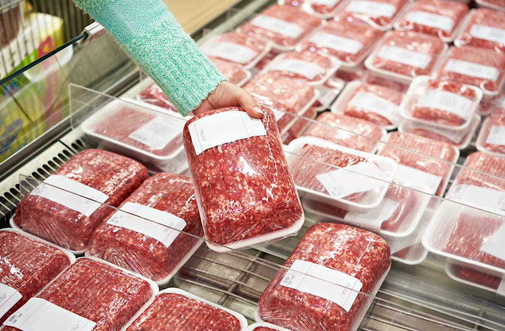 A woman picking up a ground beef package